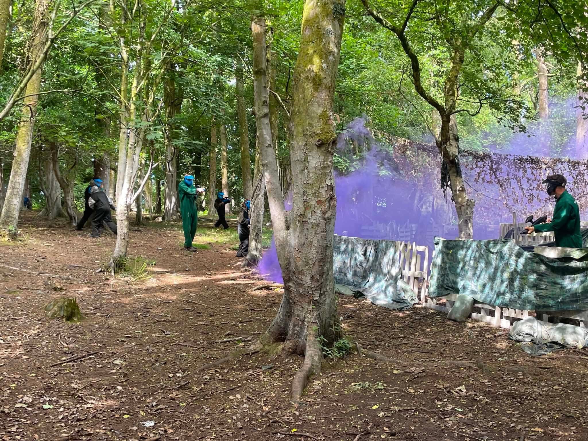 Paintball Wales players in action amid purple flares in the Snowdonia woodland